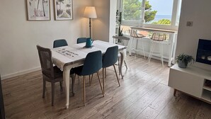 A dining area with a table set for four, a lamp, and two framed pictures on the wall. - Magnificent duplex with garden and sea view - Beach and Sanary on foot (Six-Fours-les-Plages)