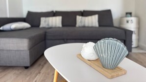 A modern living room with a grey sectional sofa, a white coffee table with decorative items, and a minimalist wall decor. - Magnificent duplex with garden and sea view - Beach and Sanary on foot (Six-Fours-les-Plages)