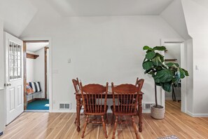 A dining area with a wooden table and chairs, a large green plant, and a view of a hallway with a door. - New Listing! Hayden Lake Guest House | Private Balcony & Lake Views (Hayden)