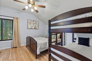 A bedroom with two wooden bunk beds, a ceiling fan, a window with curtains, and a painting on the wall. - New Listing! Hayden Lake Guest House | Private Balcony & Lake Views (Hayden)