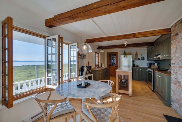 Una cocina amplia con vigas de madera, un comedor con mesa de mármol y vistas al exterior.