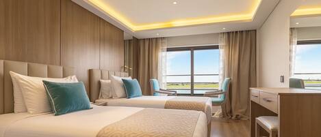 A hotel room with two beds, a desk, and a chair.