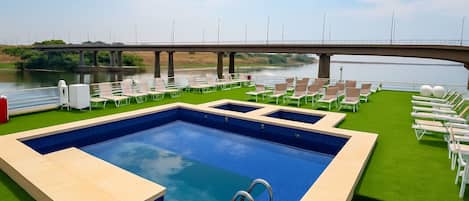 Una piscina al aire libre, sombrillas, sillones reclinables de piscina