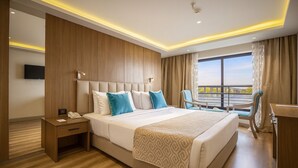 Een moderne hotelkamer met een groot bed, een bureau, een stoel, een televisie en een balkon met uitzicht.