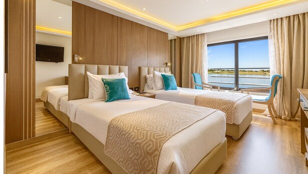 Een hotelkamer met twee bedden, een televisie, een bureau en uitzicht op het water.