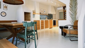 A modern kitchen with wooden cabinets, a dining area with a wooden table and chairs, and a large plant. - Authentic 4 bedroom stone house, situated in the very heart of old Komiza town (Komiža)