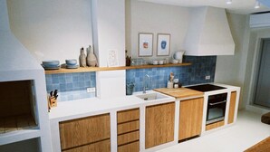 A modern kitchen with wooden cabinets, a built-in oven, and a blue tiled backsplash. - Authentic 4 bedroom stone house, situated in the very heart of old Komiza town (Komiža)
