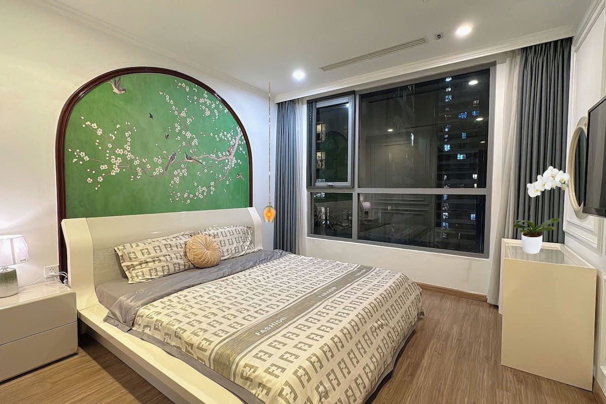 Ein modernes Schlafzimmer mit einem großen Bett, einer Wandmalerei in Grün, einem großen Fenster und einem Flachbildfernseher.