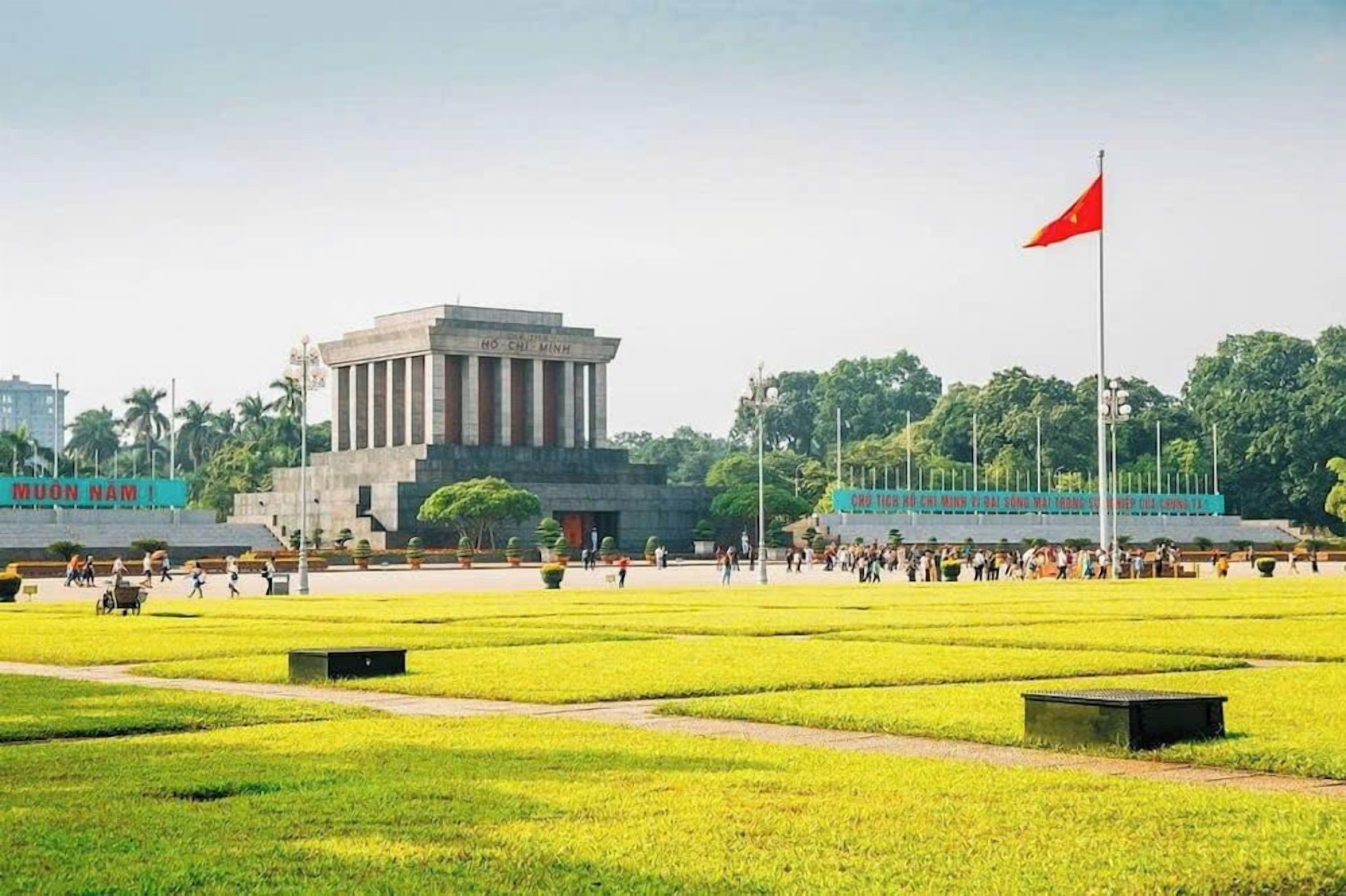 A large open plaza with a prominent building featuring columns and a flagpole with a flag.