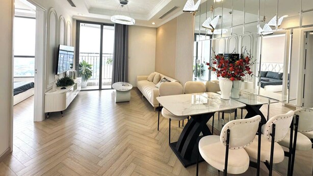 A modern hotel room with a dining area, sofa, and a balcony with a view. - Dani Apartment - Times City - Ha Noi (Hanoi)