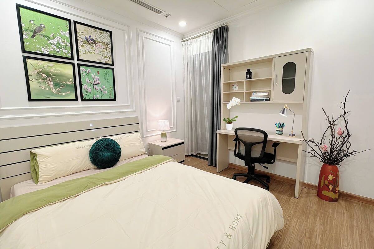 Ein Schlafzimmer mit Bett, Nachttisch, Lampe, Schreibtisch, Stuhl und einer dekorativen Vase.