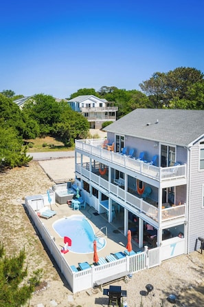 A two-story building with a pool, outdoor seating, and a view of the beach.