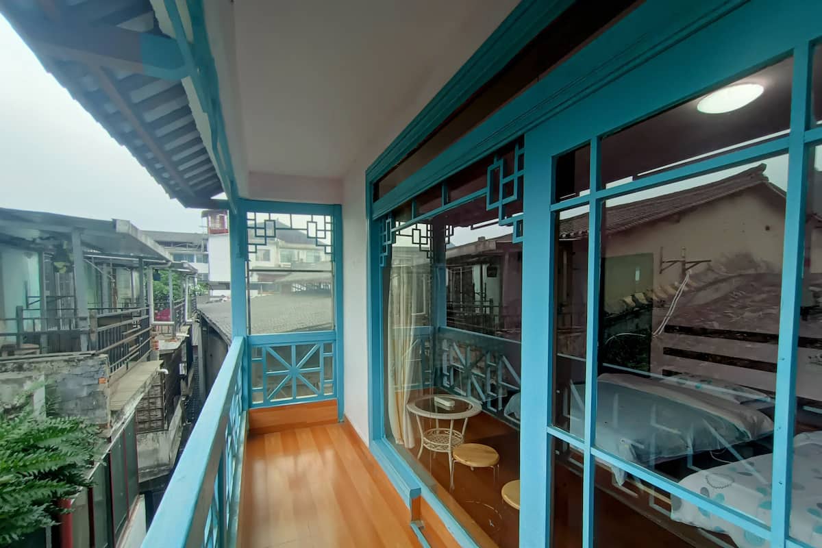 A balcony with a wooden floor, a small table, and chairs.