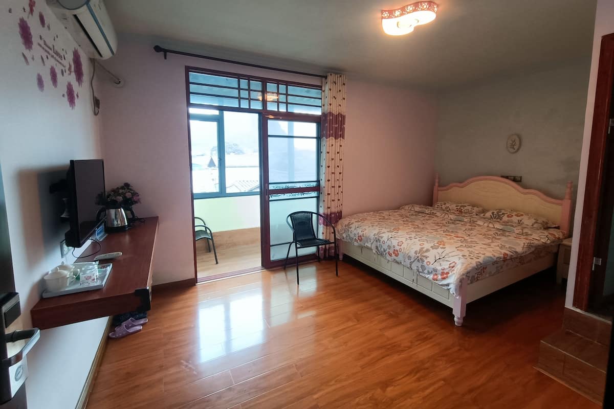 A bedroom with a bed, a desk with a computer, a chair, a window with curtains, and a ceiling light.