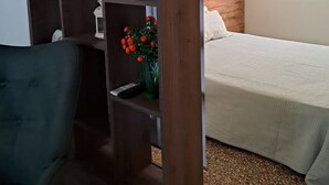 A bedroom with a bed, a nightstand, a lamp, a window, and a wooden shelf with decorative items. - Athenian Stay 301 By VPN (Athens)