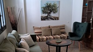 A living room with a sofa, armchairs, a coffee table, and a painting of a tree. - Athenian Stay 301 By VPN (Athens)