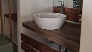 A bathroom with a white sink, wooden vanity, and a mirror. - Athenian Stay 301 By VPN (Athens)