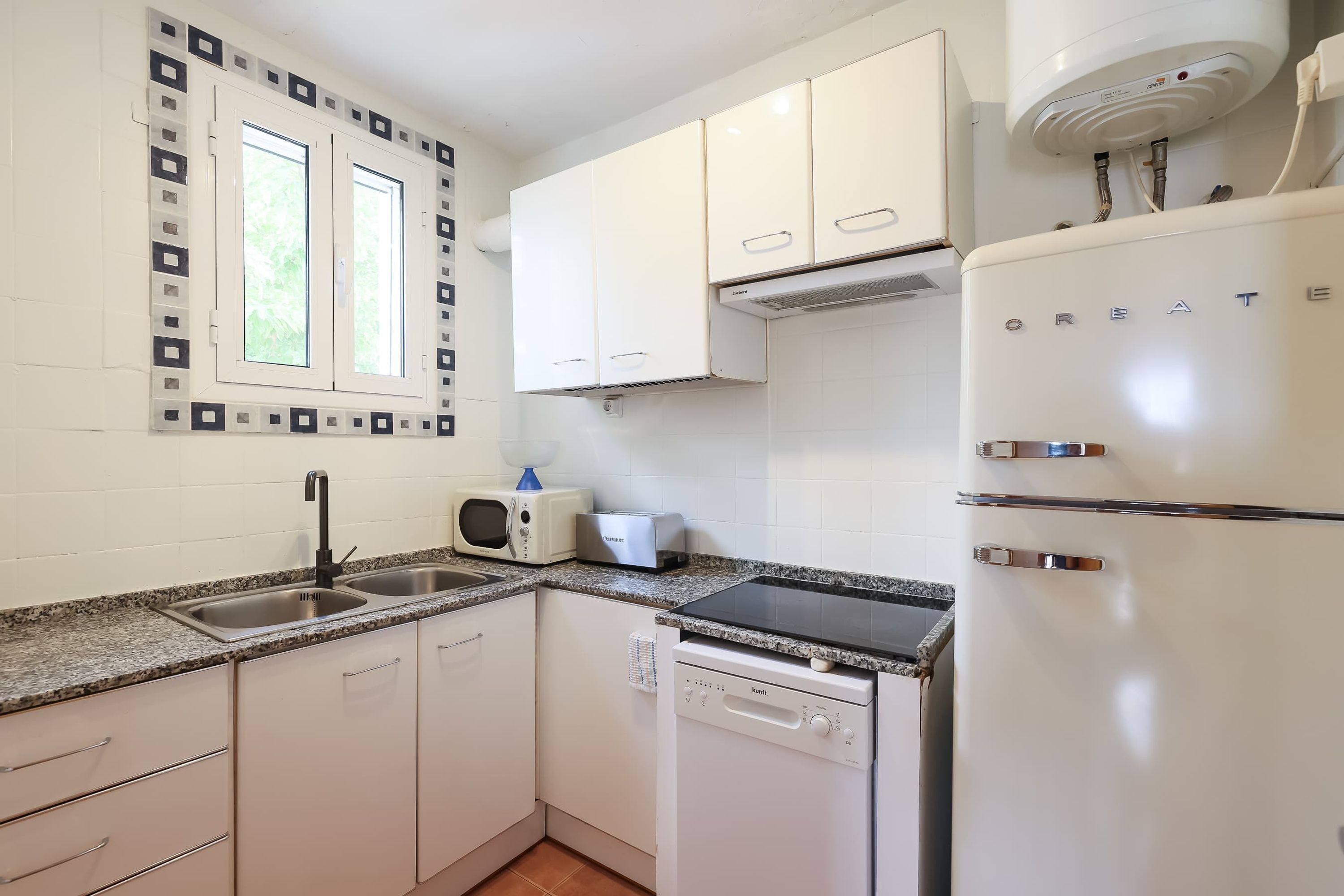 A modern kitchen with white cabinets, a built-in microwave, a dishwasher, and a refrigerator.