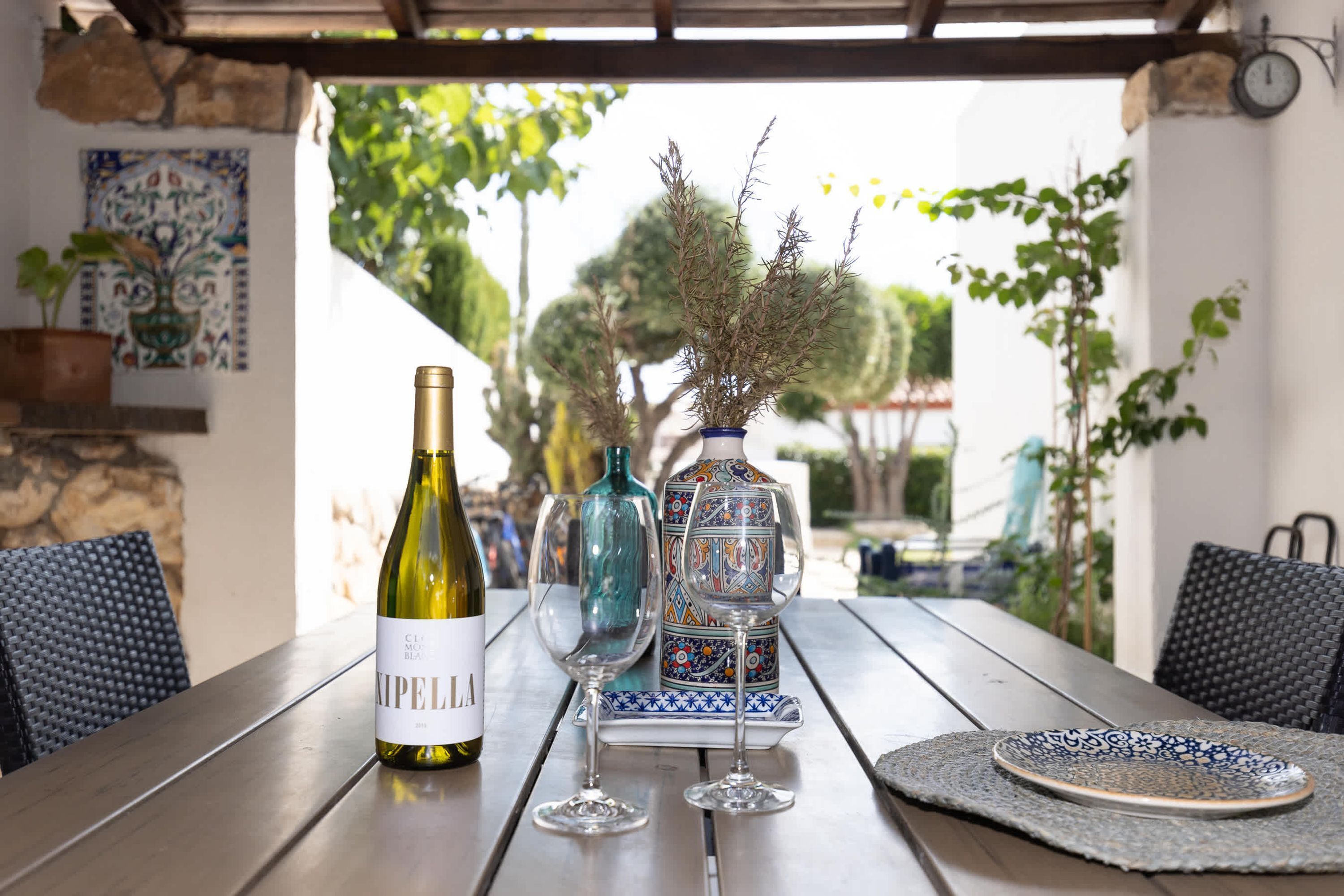 A table with a wine bottle, two glasses, and a decorative vase.