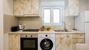 Una cocina funcional con lavadora, horno y ventana sobre el fregadero.