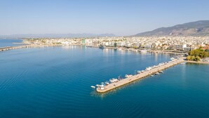 Vista aérea de una ciudad costera con un puerto deportivo, edificios y montañas al fondo.