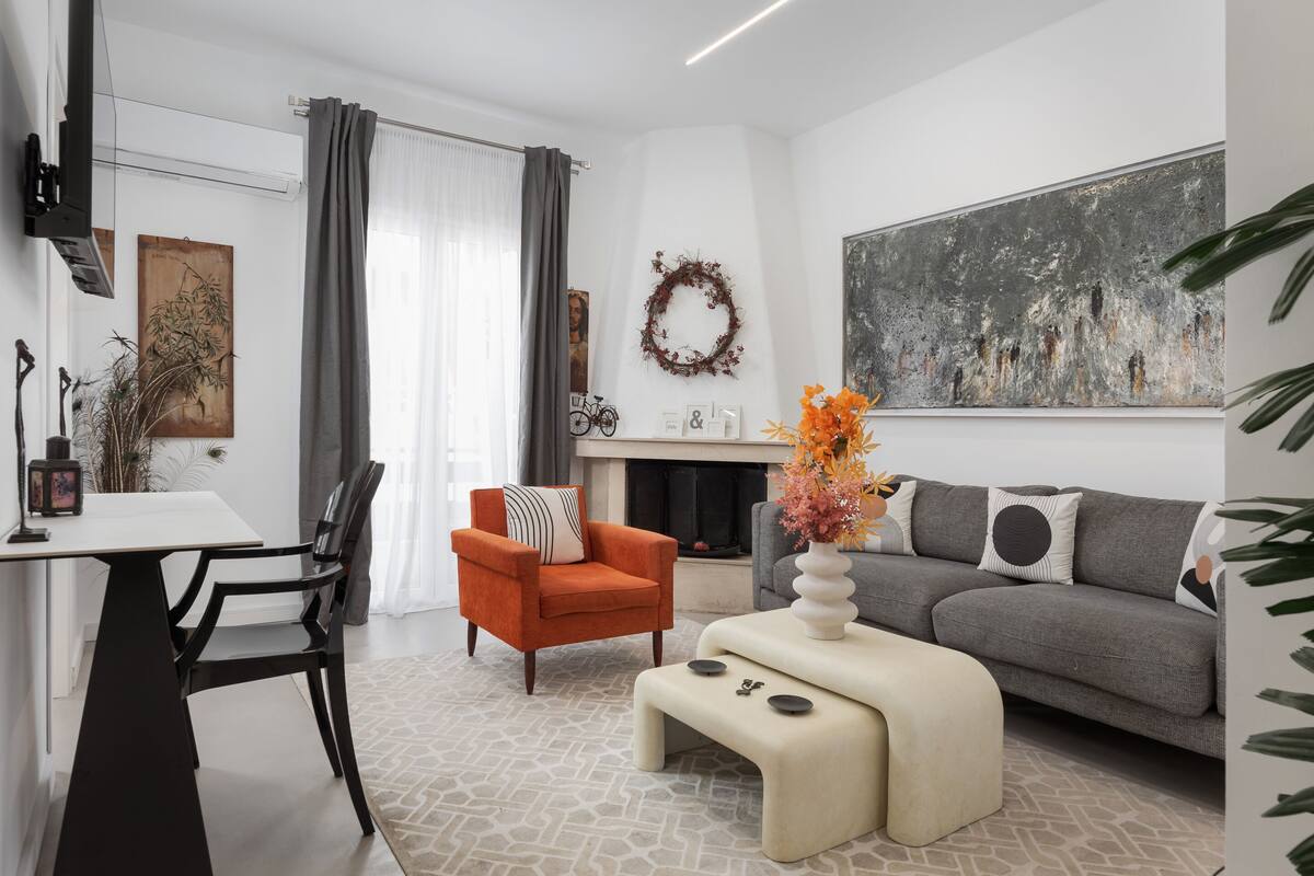 A modern living room with a sofa, a coffee table, a fireplace, and a dining area with a table and chairs.