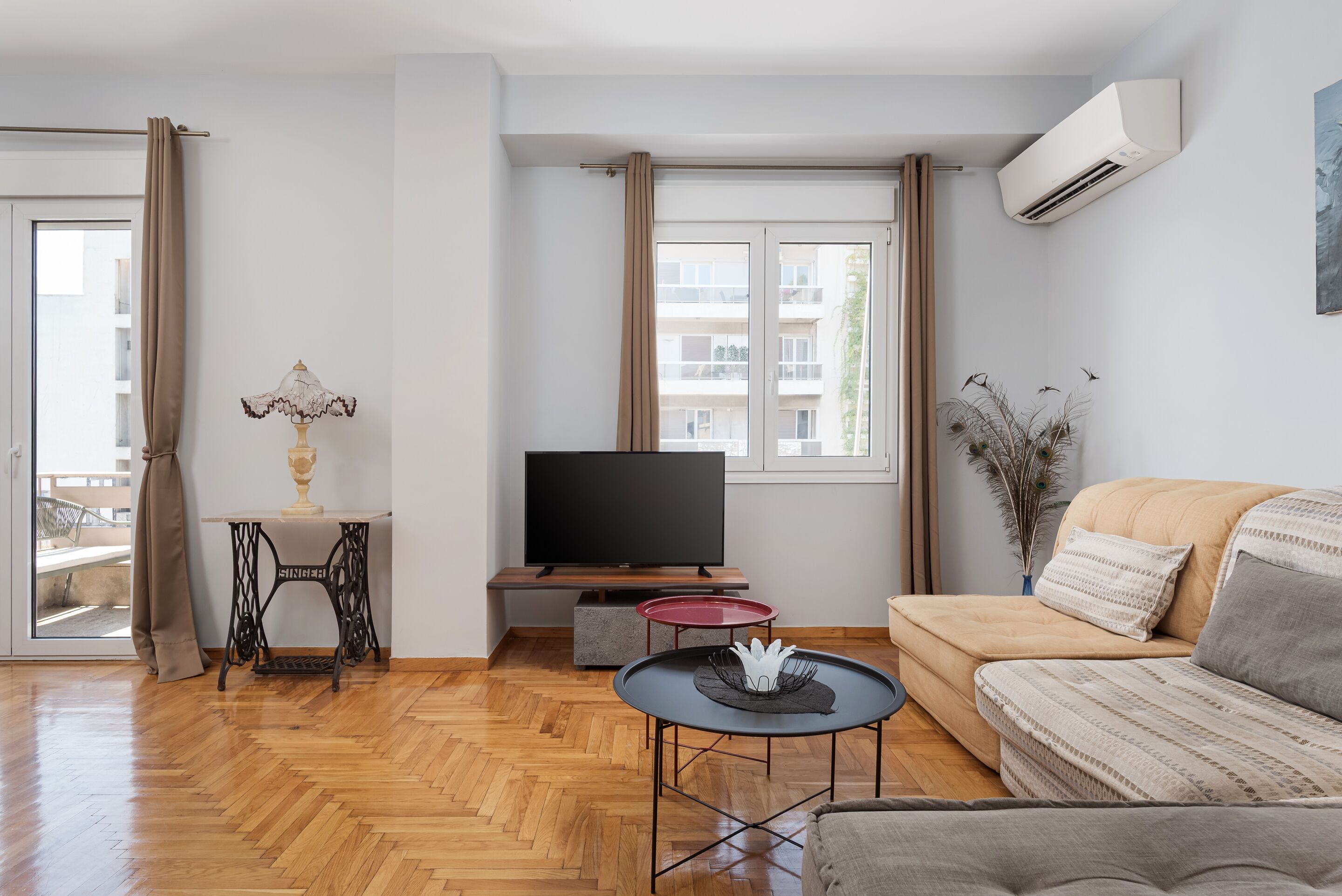 A modern living room with a sofa, a TV, a small table, and a window with curtains.