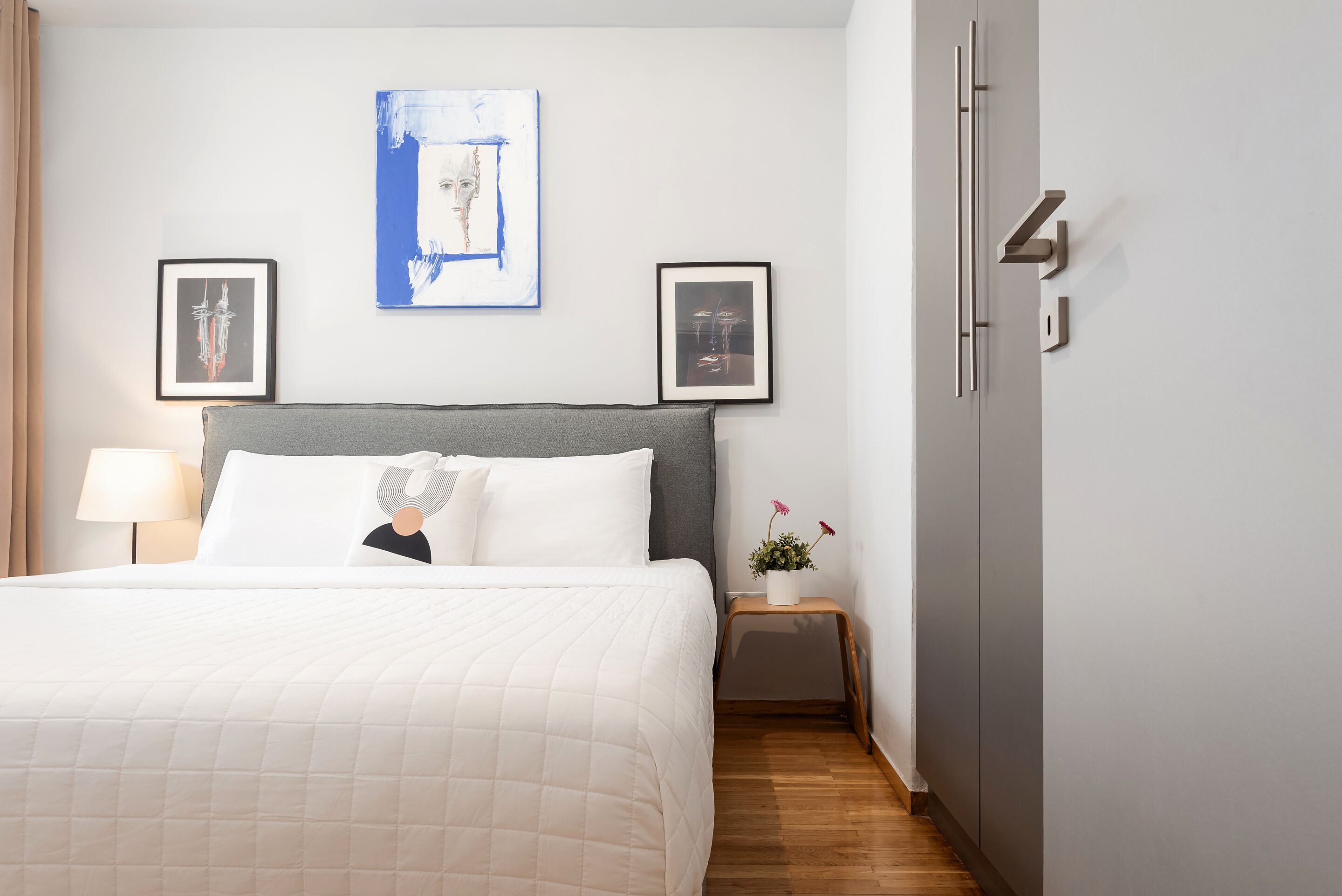 Habitación de hotel con cama, mesita de noche, lámpara, cuadro en la pared y armario.