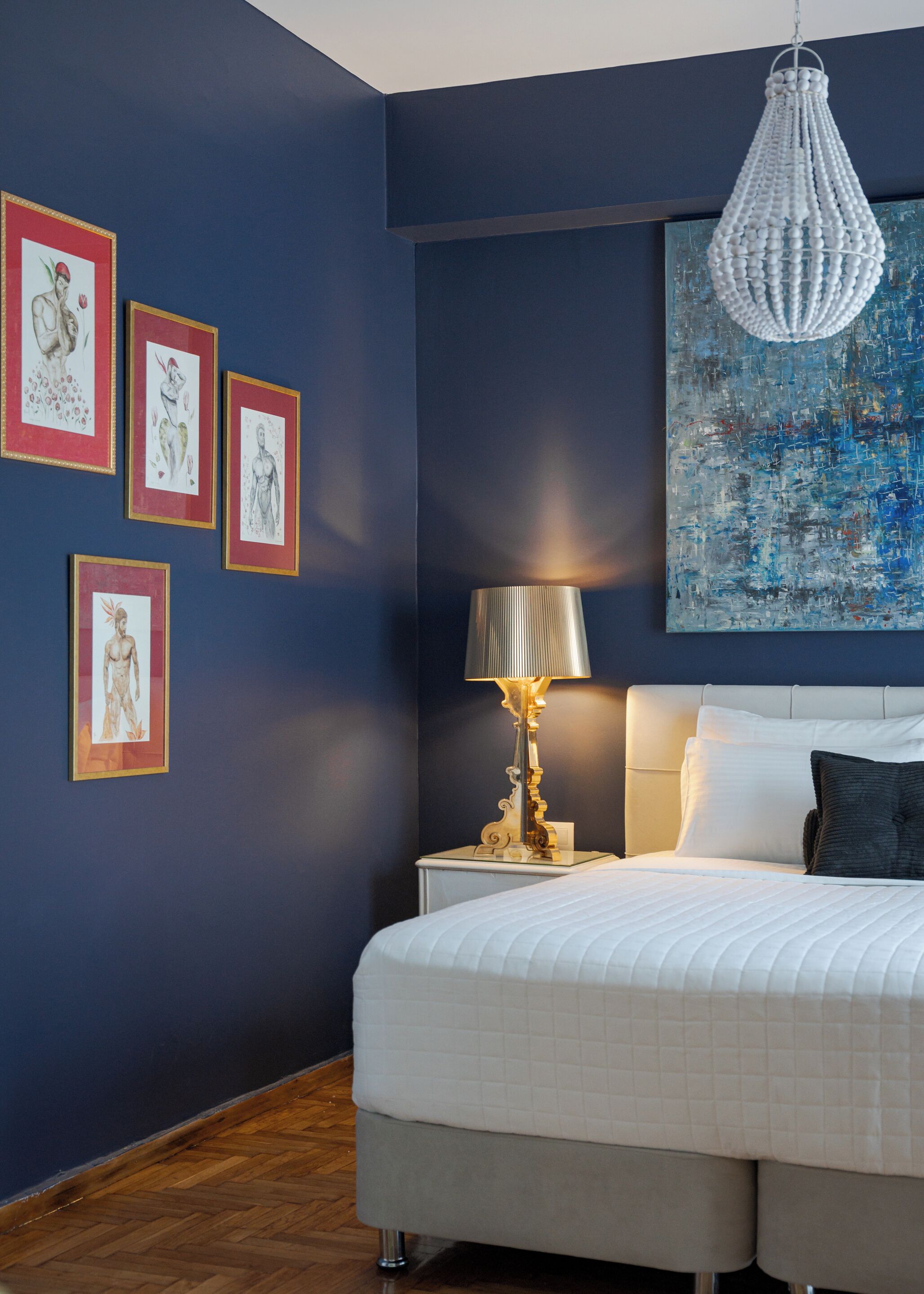 A bedroom with a bed, a nightstand, a lamp, and wall art.