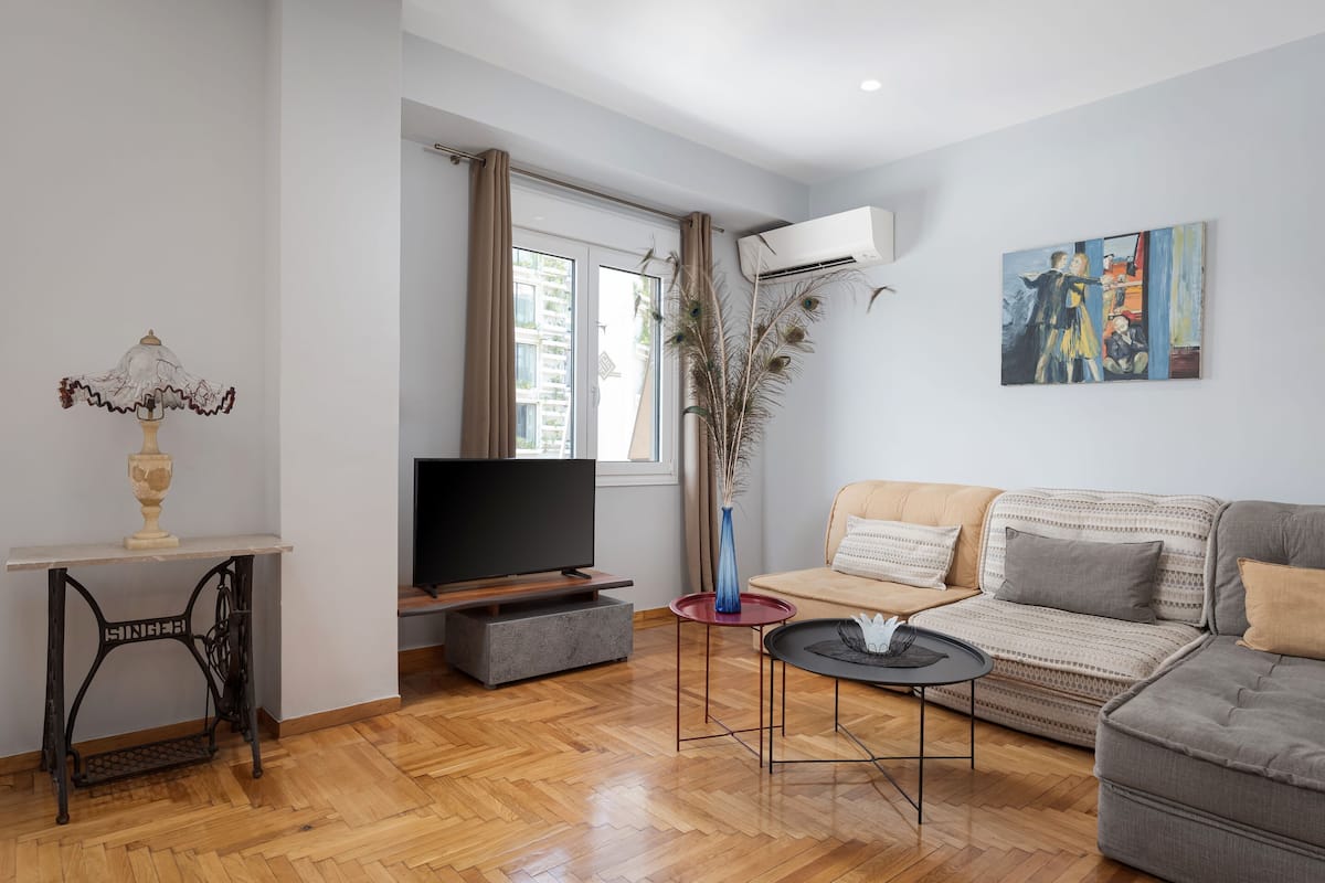 A living room with a television, sofa, and a painting on the wall.