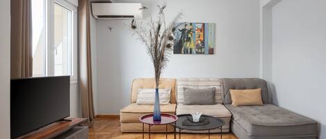 A modern living room with a grey sofa, a coffee table, and a flat-screen TV.
