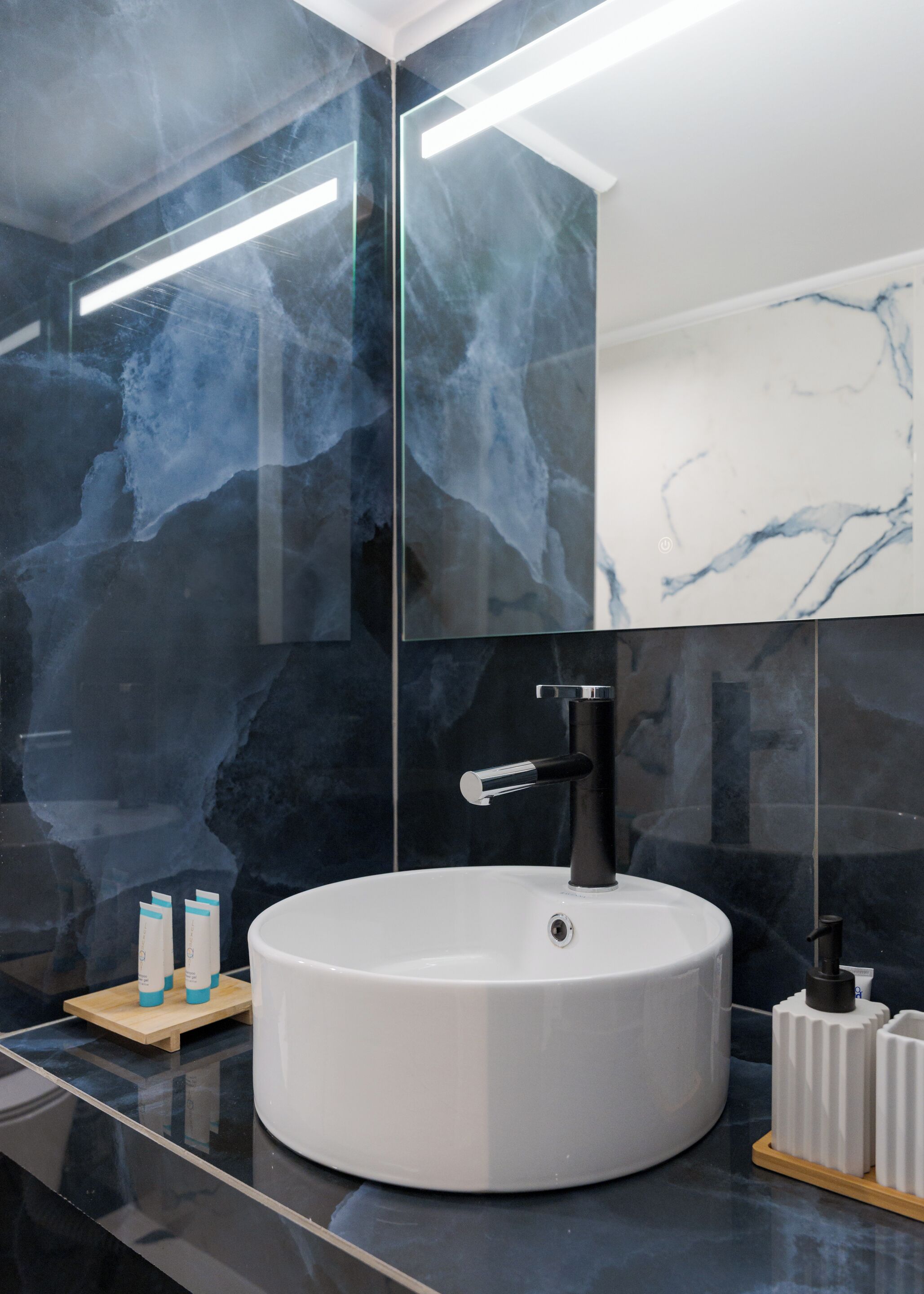 Une salle de bain moderne avec un lavabo rond blanc, un robinet noir et un grand miroir.