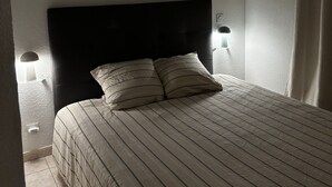 A bedroom with a large bed, two wall-mounted lamps, and two framed pictures on the wall. - An enchanting haven of calm (Andernos-les-Bains)