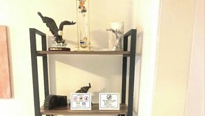 Una estantería metálica con diversos objetos, como libros, un juego de Scrabble y adornos.