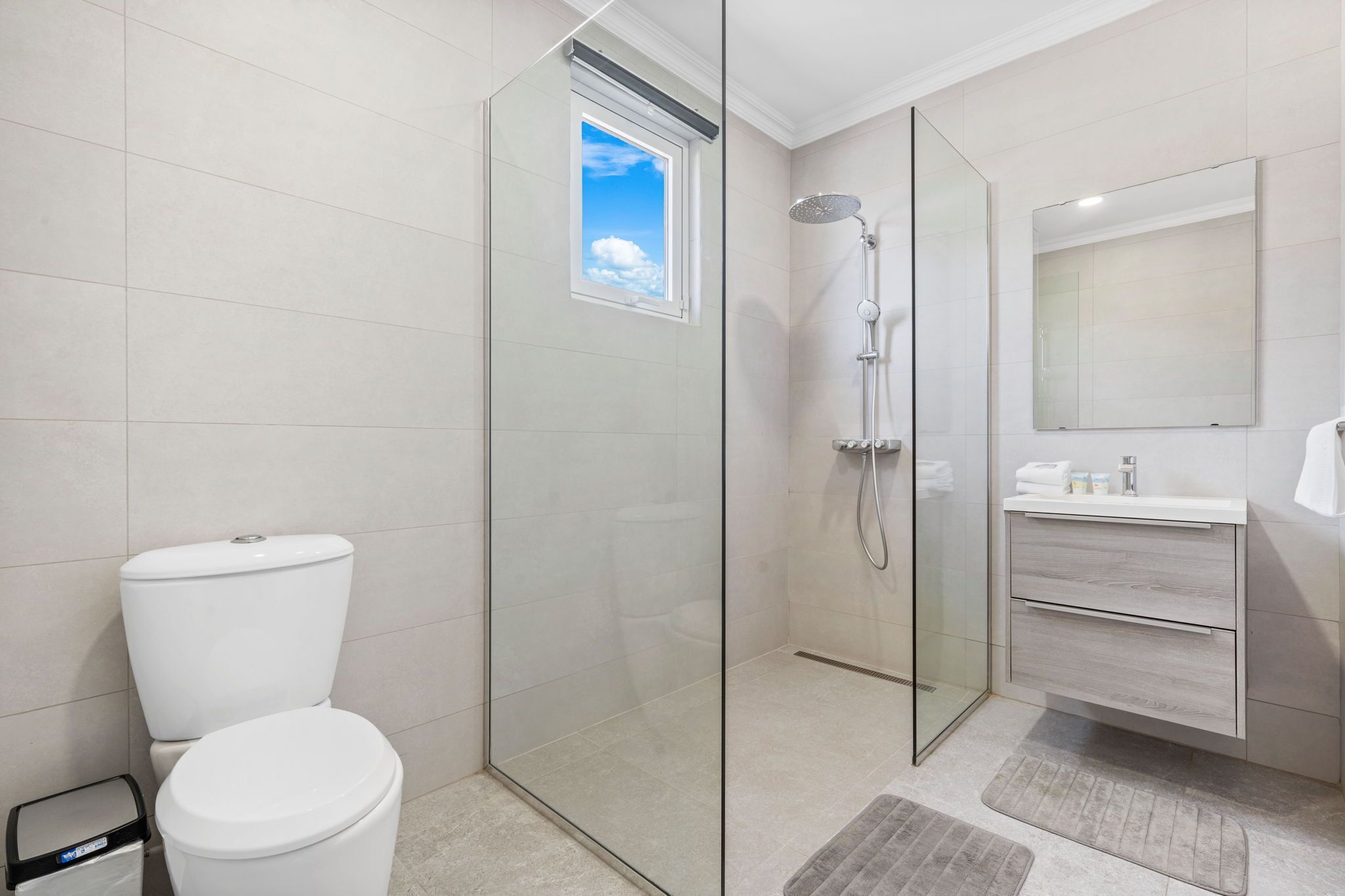 Een moderne badkamer met een douchecabine van glas, een toilet en een wastafel met spiegel.