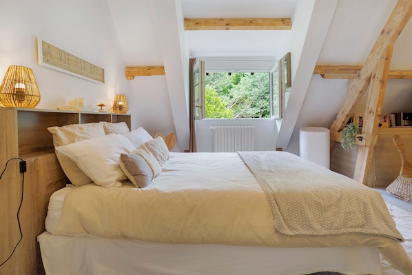Un dormitorio con cama, lámparas de noche, una ventana y vistas al verdor.