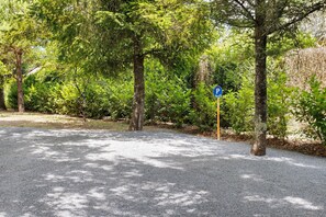 A parking area with a blue parking sign, surrounded by trees and greenery. - Maraval – Cozy air-conditioned suite in a private home with garden and pool access in Périgueux (Trélissac)