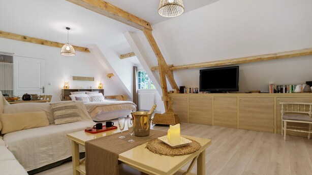 Quarto de loft aconchegante com cama, mesa de cabeceira e televisão.