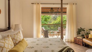A four-poster bed with a floral bedspread, a balcony with a table and chairs, and a leather sofa. - Elivaas Opalys (Arpora)