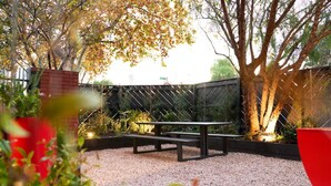 A patio area with a wooden bench and a red planter.