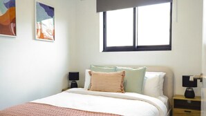 Une chambre bien rangée, avec un lit, deux tables de chevet et une fenêtre.