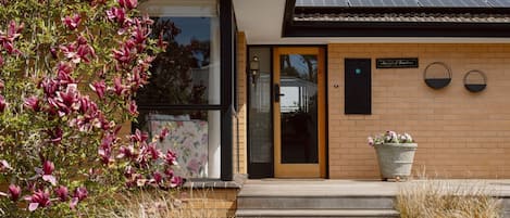 A modern house with a brick exterior, a glass door entrance, and a solar panel roof.