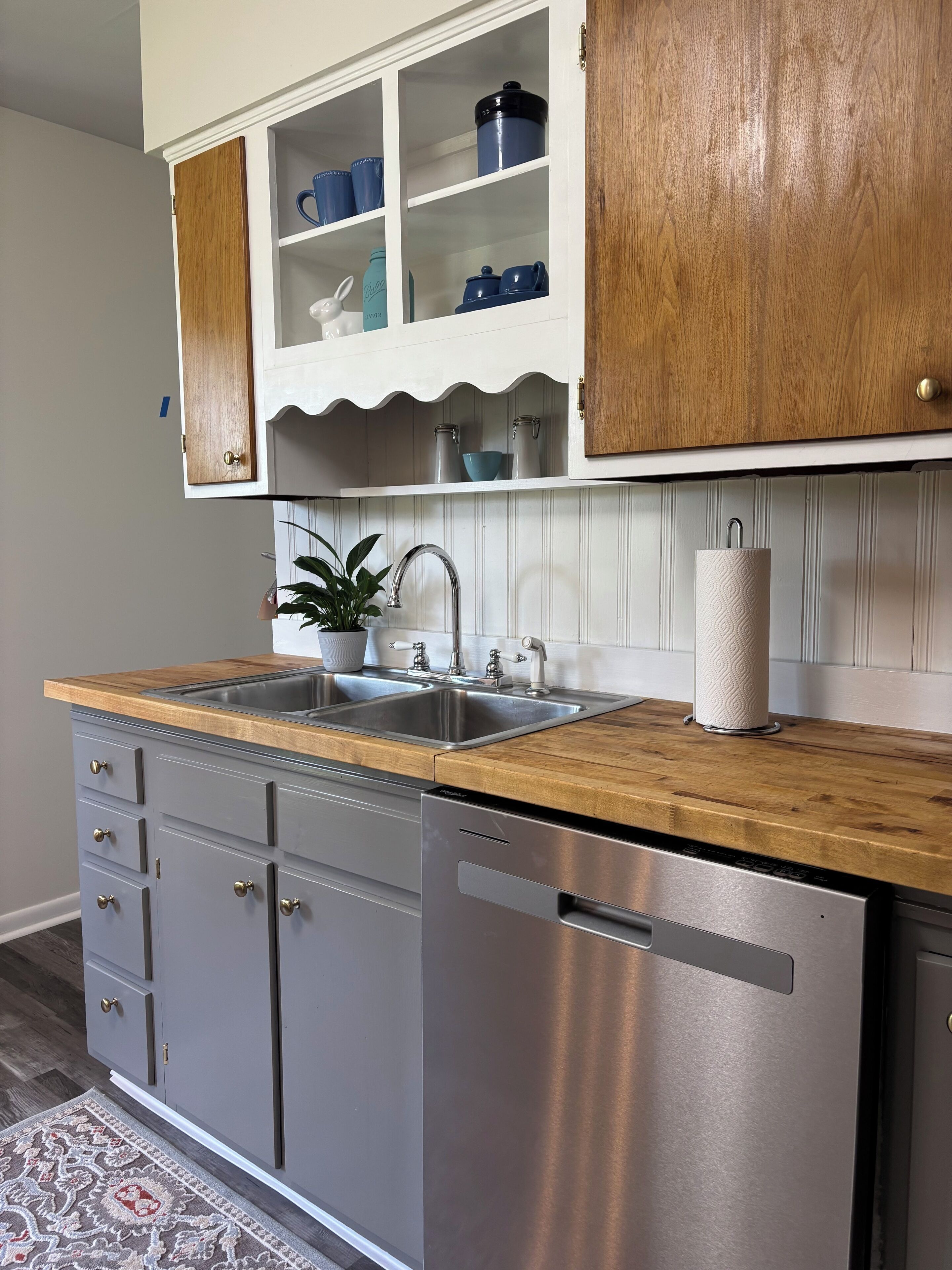 A kitchen with a wooden countertop, stainless steel appliances, and white cabinetry.