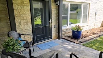 A patio with two wicker chairs, a black door, and a blue potted plant.