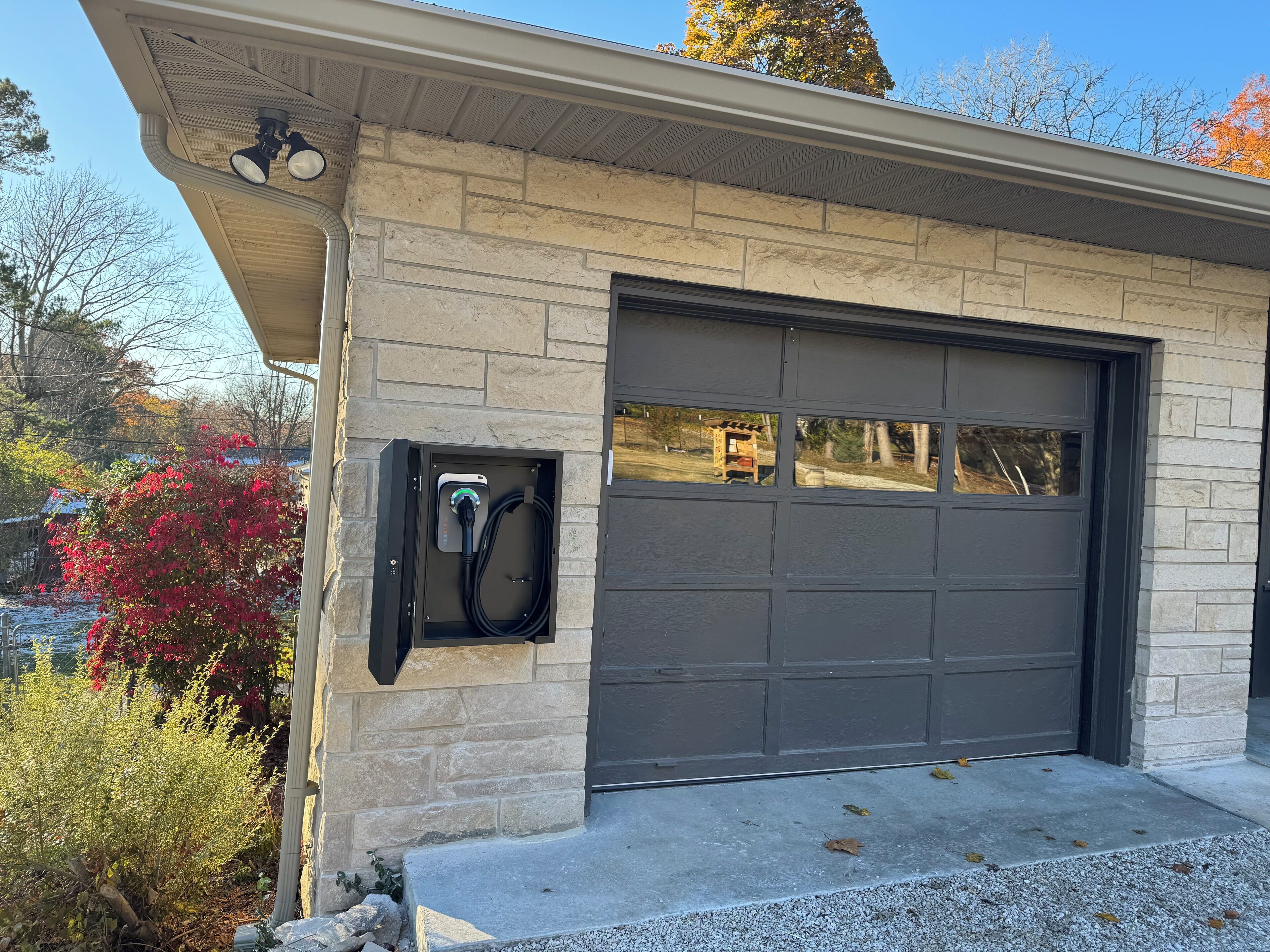 A garage with a charging station, a stone facade, and a view of the surrounding area.