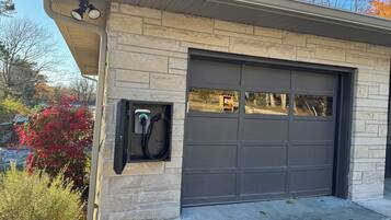 A garage with a charging station, a stone facade, and a view of the surrounding area.