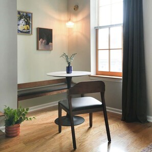 A dining area with a round table, a chair, a potted plant, and a painting on the wall. - Charming 1BDR With King Bed in Rittenhouse Square (Philadelphia)