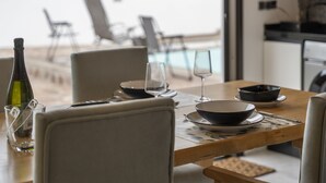 A dining table set with plates, bowls, and wine glasses, with a bottle of wine and a glass of water. - 'Vista Teide' Vacation Apartment with Sea View, Wi-Fi, and Air Conditioning (Tacoronte)