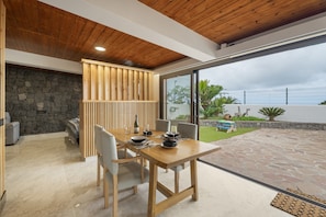 Un espace de restauration moderne avec une table et des chaises en bois, un mur en pierre et une vue sur un jardin.