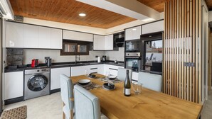 A modern kitchen with a wooden ceiling, built-in appliances, and a dining area with a wooden table and chairs. - 'Vista Teide' Vacation Apartment with Sea View, Wi-Fi, and Air Conditioning (Tacoronte)